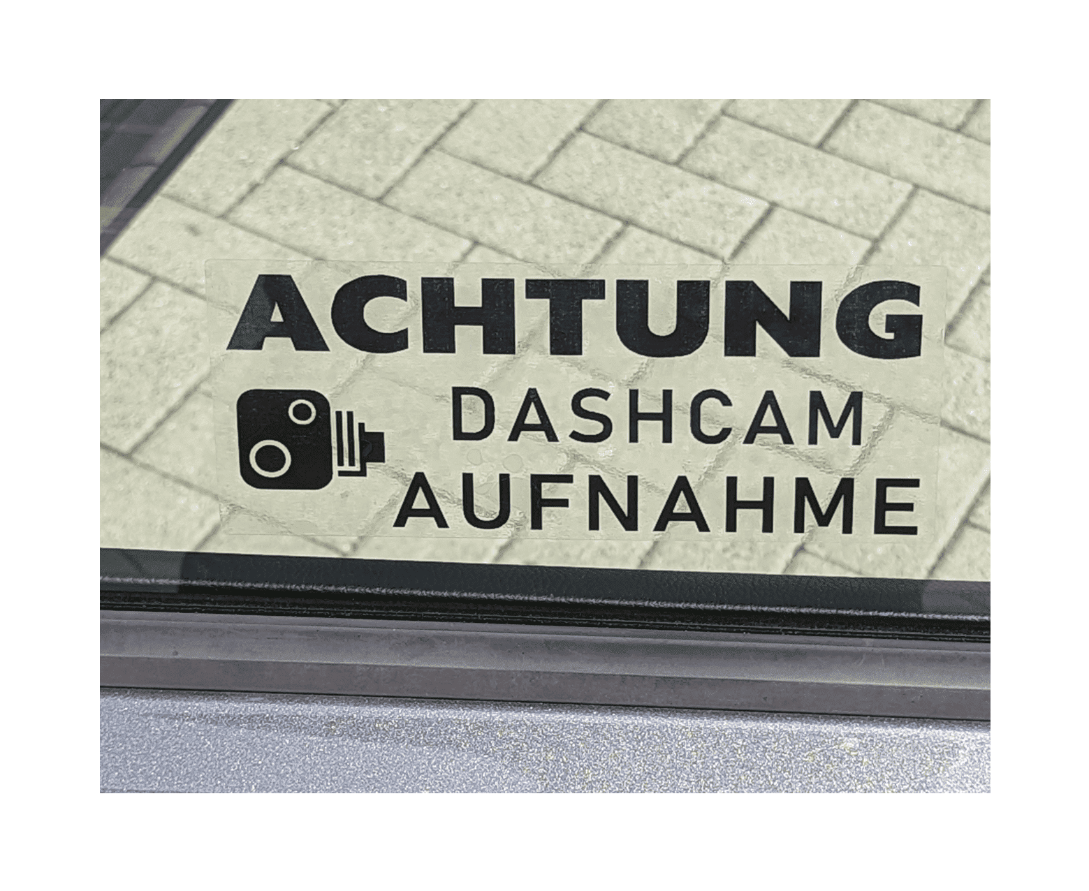 Autosticker mit der Aufschrift "ACHTUNG DASHCAM AUFNAHME" und einem Kamera-Symbol auf einer Autoscheibe.