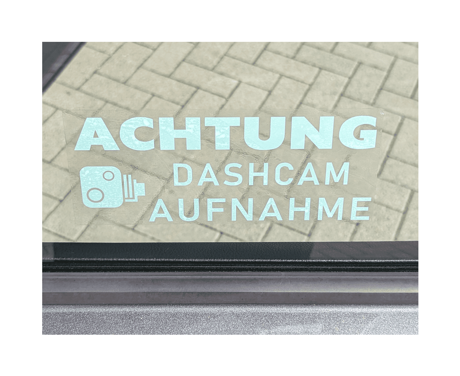 Autosticker mit Text "ACHTUNG DASHCAM AUFNAHME" und Kamerasymbol auf Autofenster montiert.